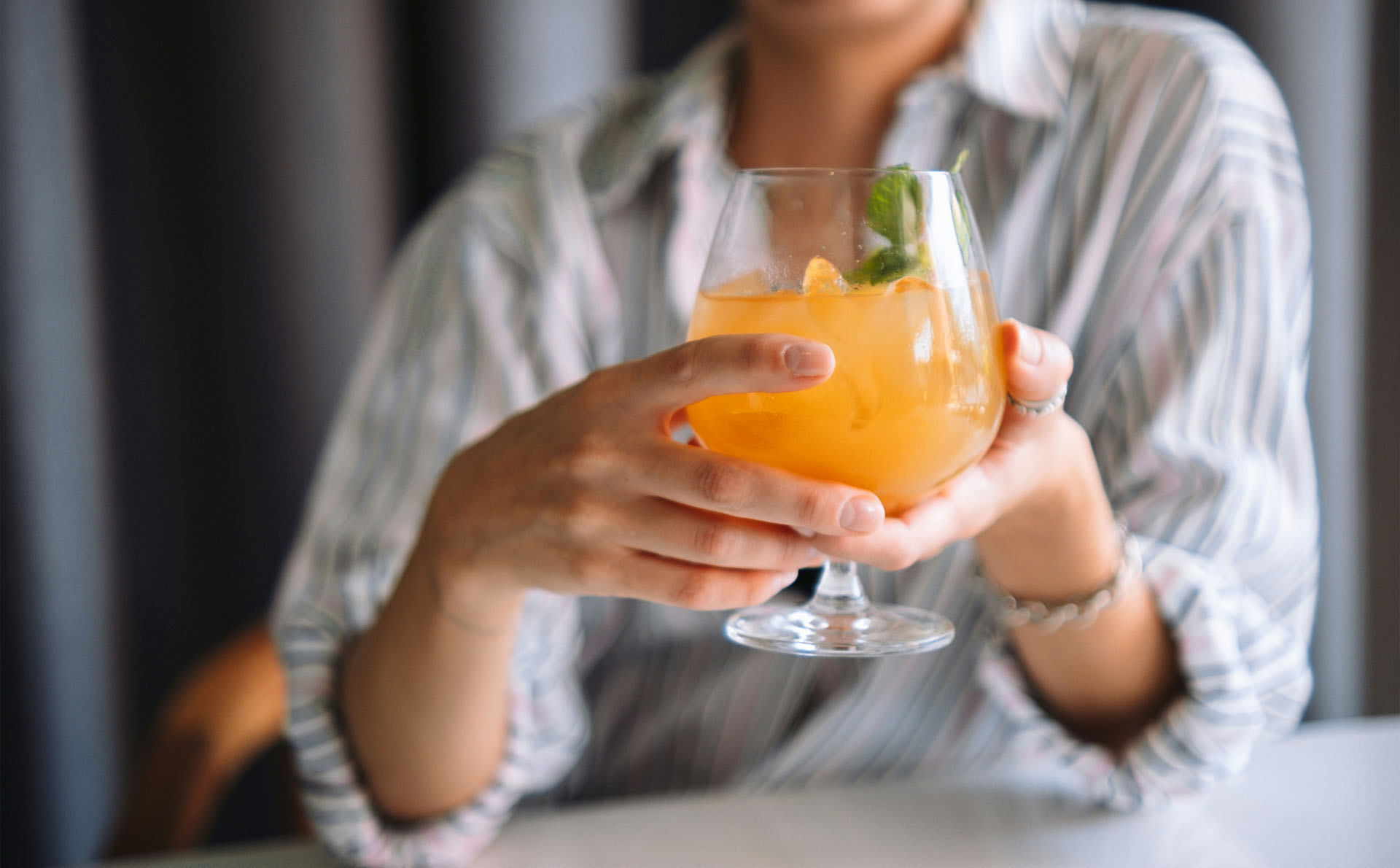 Hand hält einen Cocktail mit Eis und Minze.