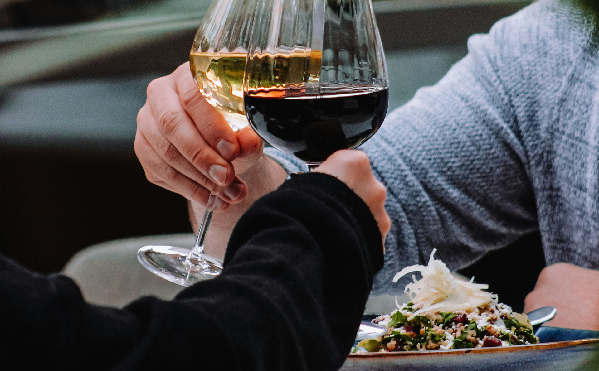 Zwei Personen stoßen mit Wein beim Essen an