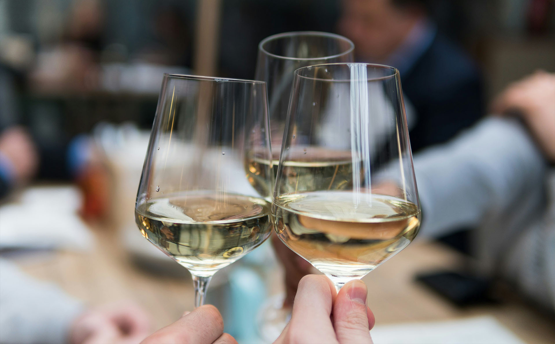 Drei Weißweingläser beim Anstoßen