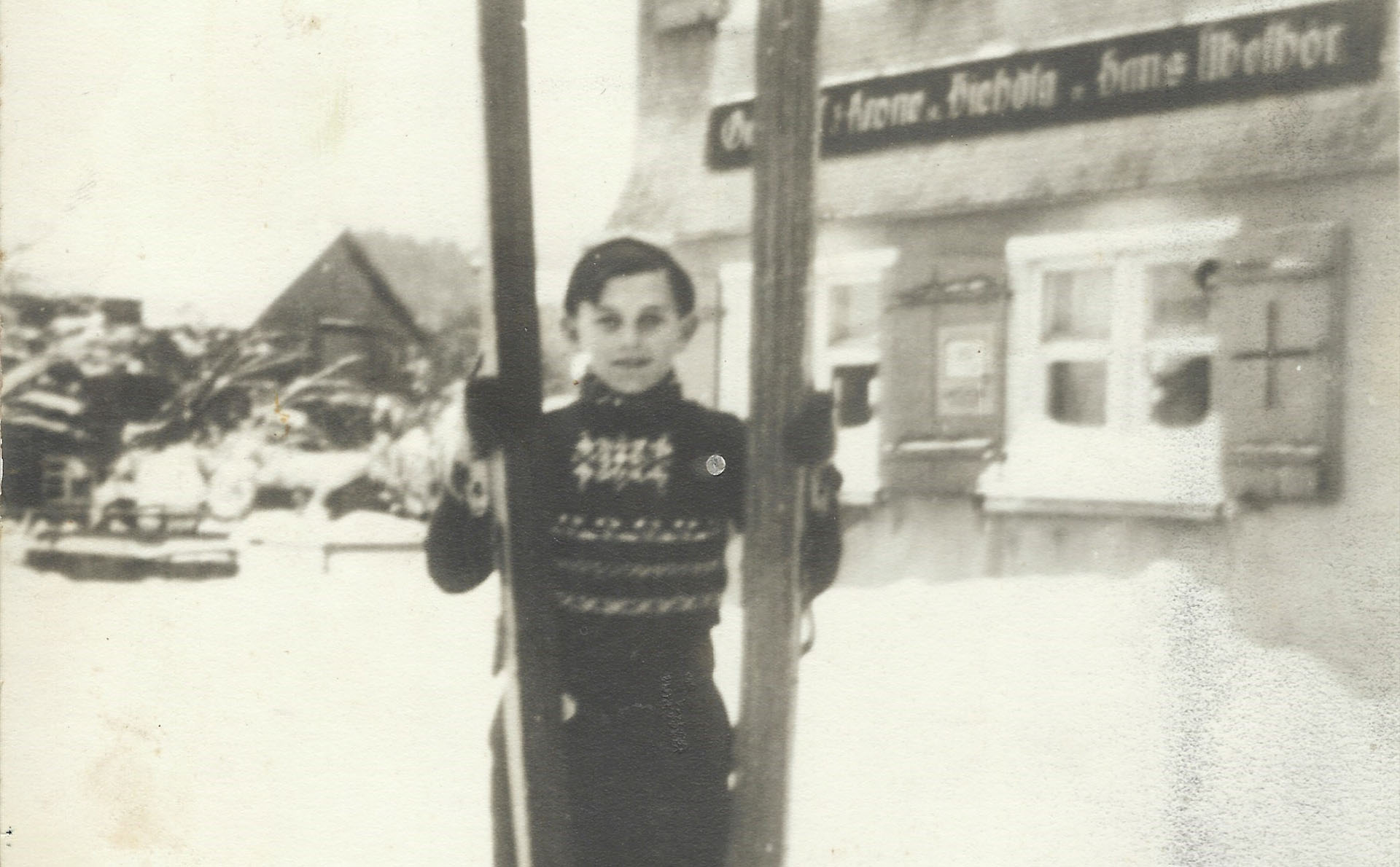 Johann Übelhör mit Sprungskiern im Schnee vor Gasthaus