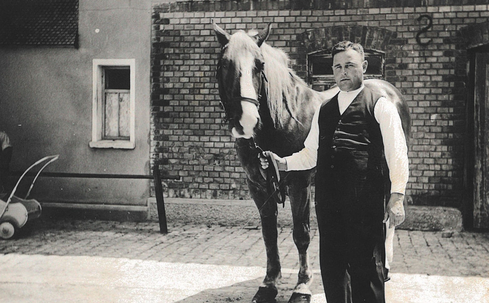 Mann mit Pferd vor Stallgebäude, historisches Familienfoto