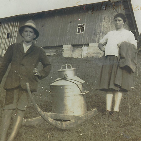 Bauernpaar mit Milchkannen vor einem Hof im Allgäu
