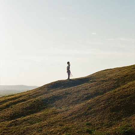 Person steht achtsam auf einem Hügel in der Natur
