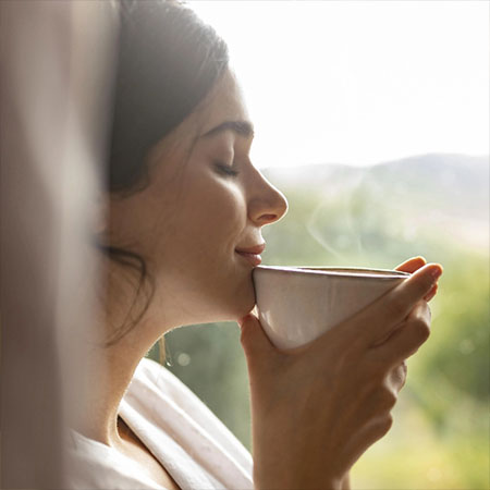 Frau genießt eine Tasse Kaffee am Fenster