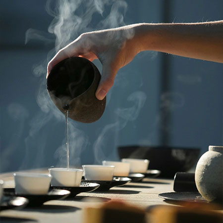 Heißer Tee wird in kleine Tassen eingeschenkt