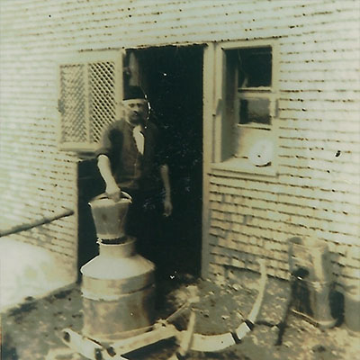 Mann mit Milchkannen vor einem Gebäude