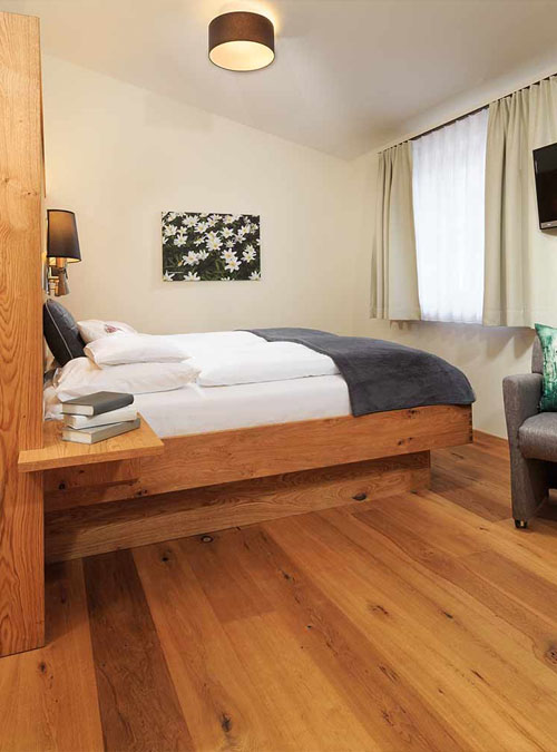 Helles Doppelzimmer mit Holzbett und Sitzbereich