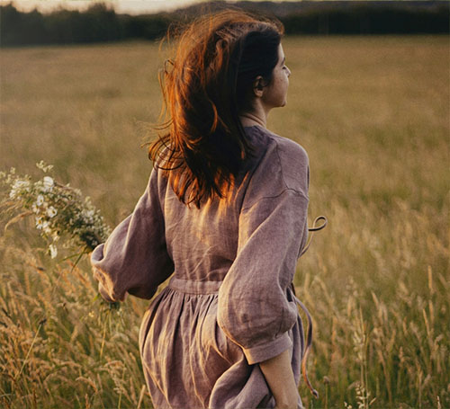 Frau geht durch eine Wiese im Abendlicht