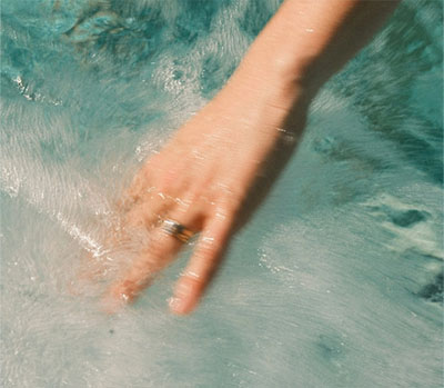 Hand gleitet durch klares Wasser