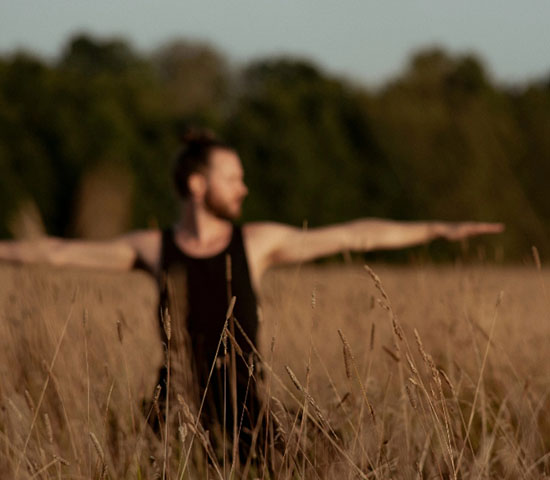 Mann macht Yoga auf einer Wiese in der Natur