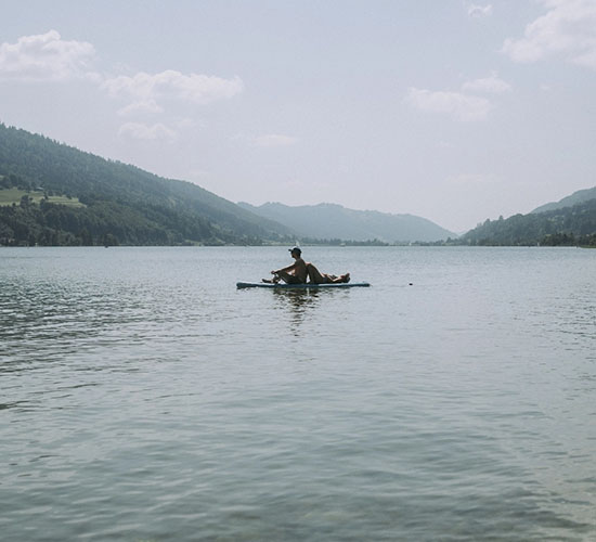 Person fährt Stand-Up-Paddle auf dem Großen Alpsee im Allgäu