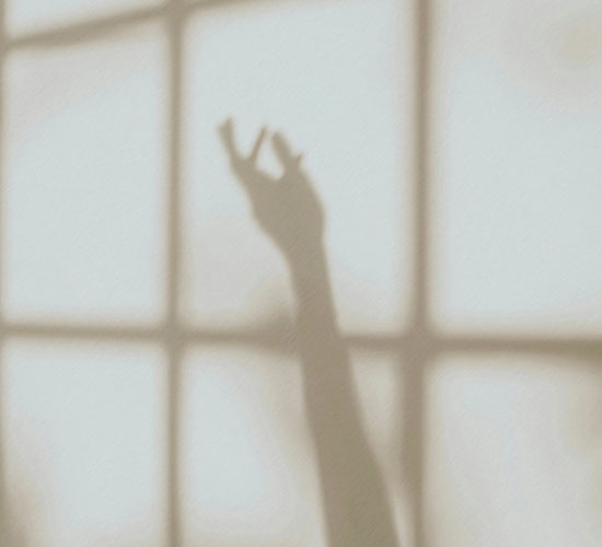 Schatten einer erhobenen Hand vor einem Fenster