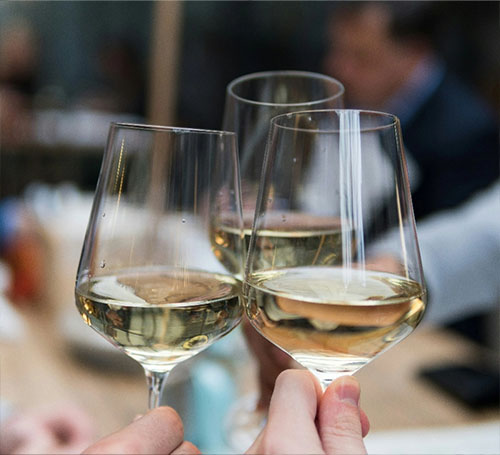 Menschen stoßen mit Weißwein im Restaurant an