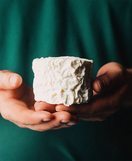 Stück Käse wird in zwei Händen gehalten