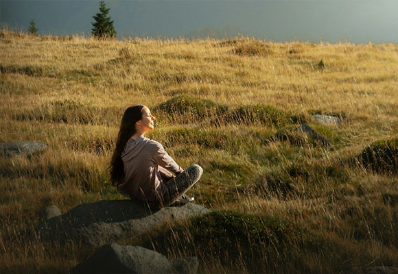 Frau sitzt entspannt in einer Wiese und genießt die Natur im Allgäu