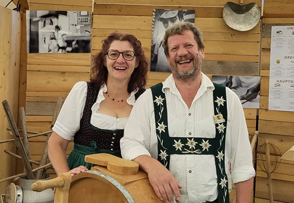 Traditionelles Käserpaar präsentiert Käseproduktion in Tracht