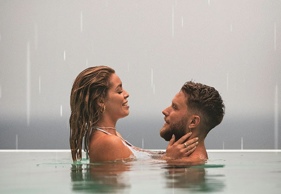 Paar umarmt sich entspannt im Pool bei leichtem Regen