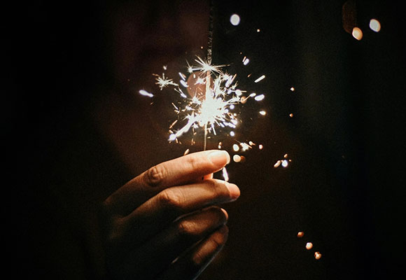 Hand hält eine funkelnde Wunderkerze in der Dunkelheit