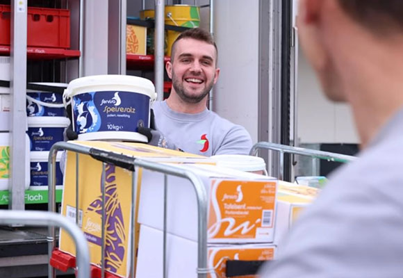 Mitarbeiter liefert frische Lebensmittelkisten aus einem Transportfahrzeug