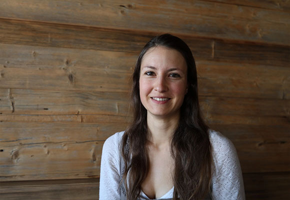 Mitarbeiterin mit langen dunklen Haaren und weißer Bluse