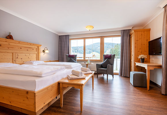 Helles Doppelzimmer mit großem Fenster, Sesseln und Holzmöbeln