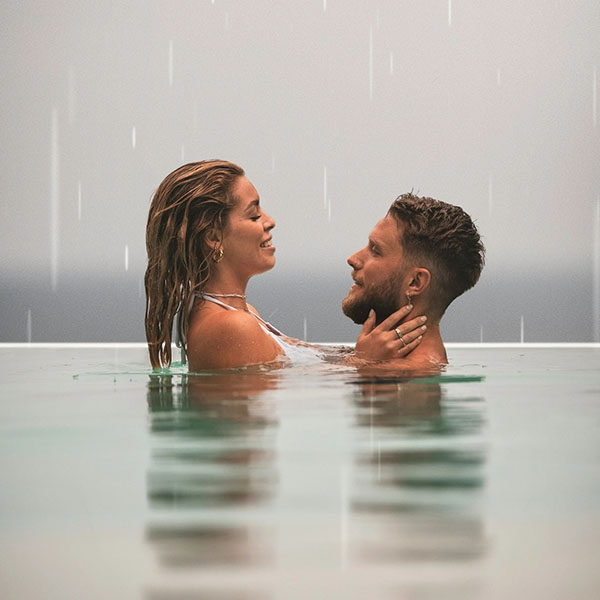 Paar steht sich nah in einem Pool im Regen und schaut sich an