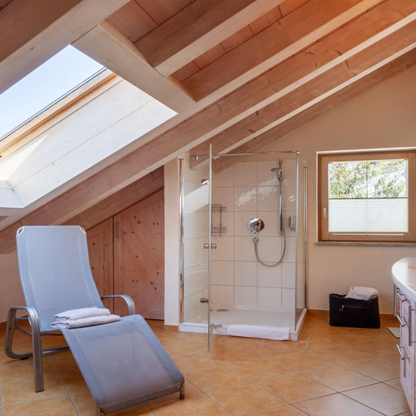 Badezimmer mit Dusche und Liegestuhl unter Dachschräge
