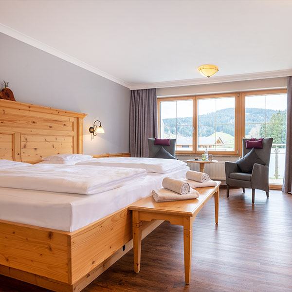 Helles Doppelzimmer mit Holzbett und Blick zum Balkon