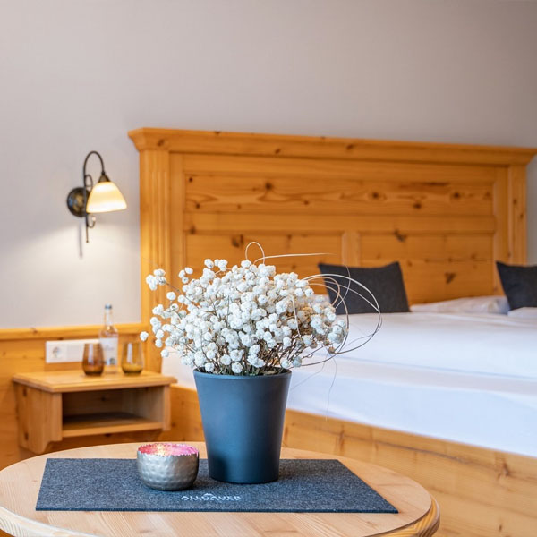Detailaufnahme eines Blumenarrangements vor einem Bett