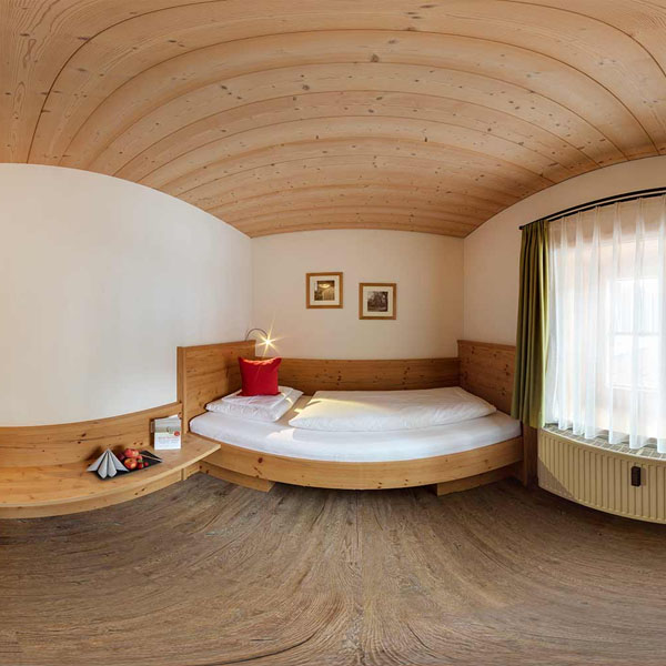 Weitwinkelaufnahme eines Einzelzimmers mit Bett und Fenster