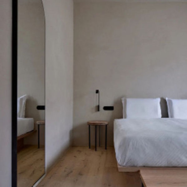 Minimalistisch eingerichtetes Schlafzimmer mit Bett und Spiegel