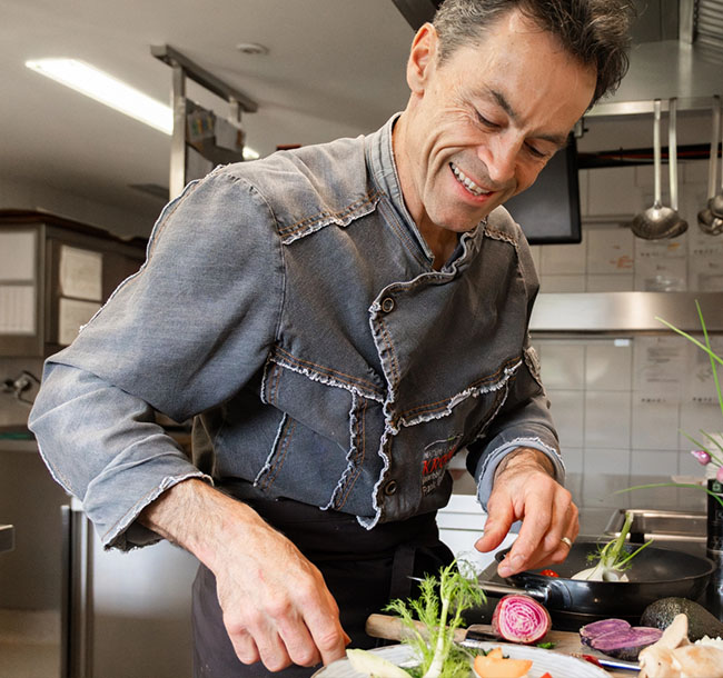 Koch richtet konzentriert frische Zutaten in der Küche an