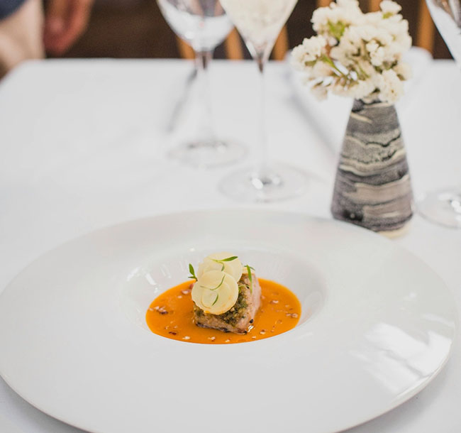 Gourmetgericht mit Sauce und dekorativer Garnitur auf weißem Teller