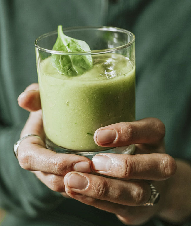 Grüner Smoothie in einem Glas mit frischem Blatt als Dekoration
