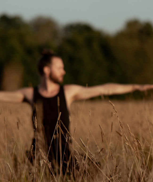 Mann macht Yoga in einem Feld mit ausgestreckten Armen