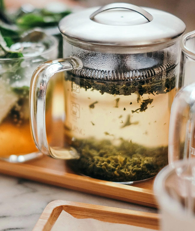 Kräutertee wird in einer Glaskanne aufgegossen