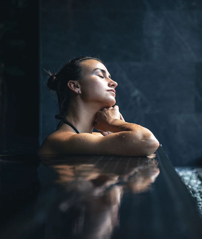Frau entspannt mit geschlossenen Augen im Wasser eines Pools