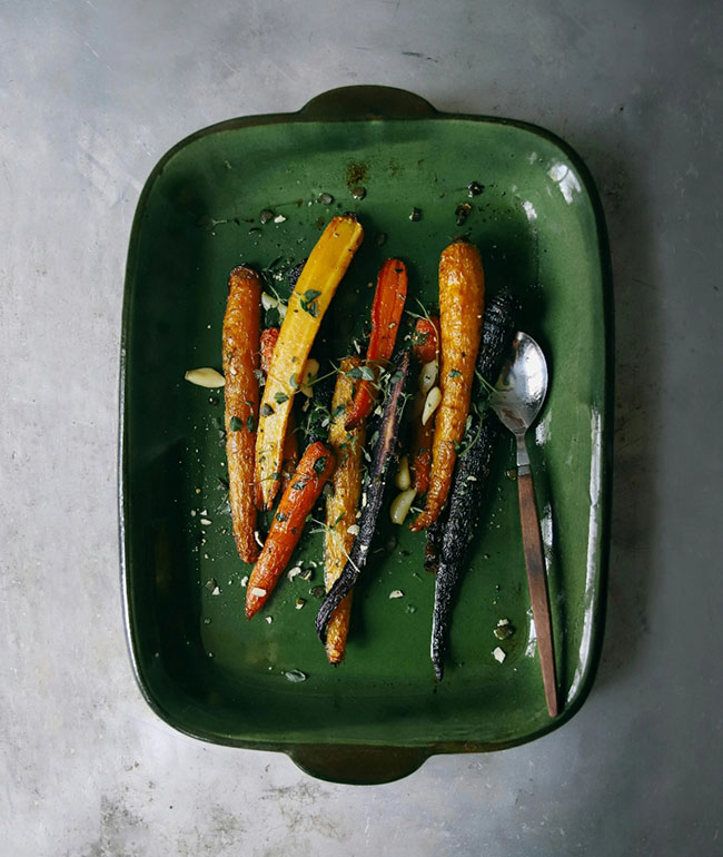 Gebackene Karotten auf einem Teller mit Kräutern und Nüssen