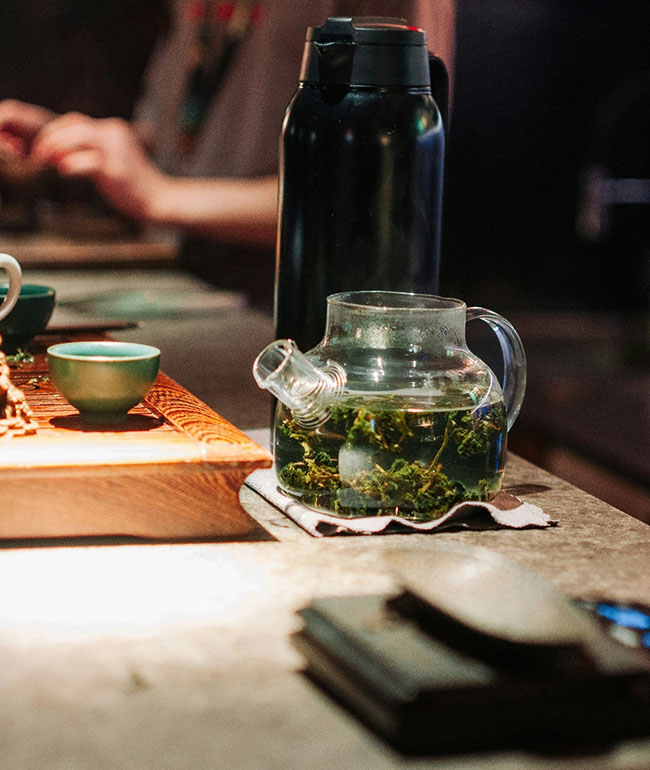 Glaskanne mit frisch aufgegossenem Kräutertee auf einem Tisch
