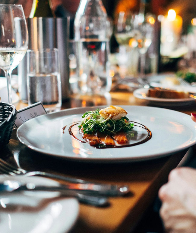 Fein angerichtetes Gourmetgericht auf einem Teller im Restaurant mit Kerzenlicht
