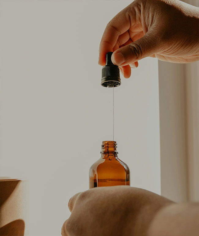 Tropfen Naturkosmetiköl wird mit einer Pipette in eine Flasche gegeben