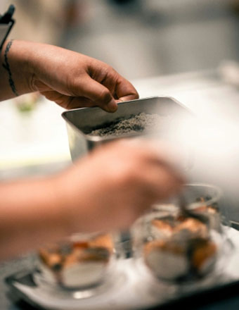 Koch richtet ein Dessert in kleinen Gläsern in der Restaurantküche an