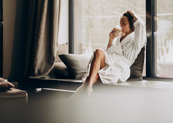 Frau im Bademantel genießt eine Pause am Fenster im Spa
