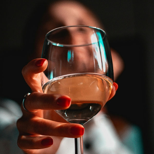 Frau hält Glas Weißwein in gemütlicher Atmosphäre