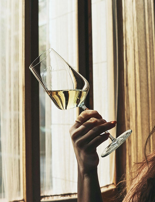 Weißwein im Glas vor Fenster im Wellnesshotel