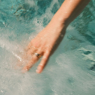 Hand gleitet durch warmes Wasser im Spa